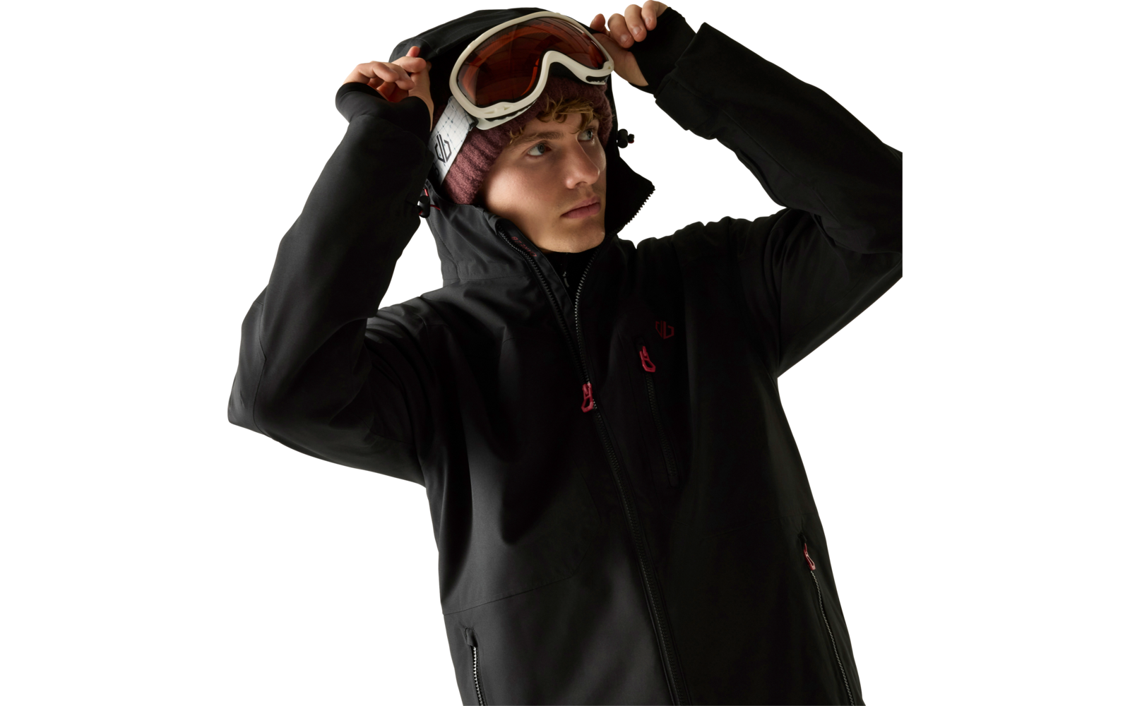 Person in schwarzer Skijacke und Strickmütze setzt eine Skibrille auf, heller Hintergrund
