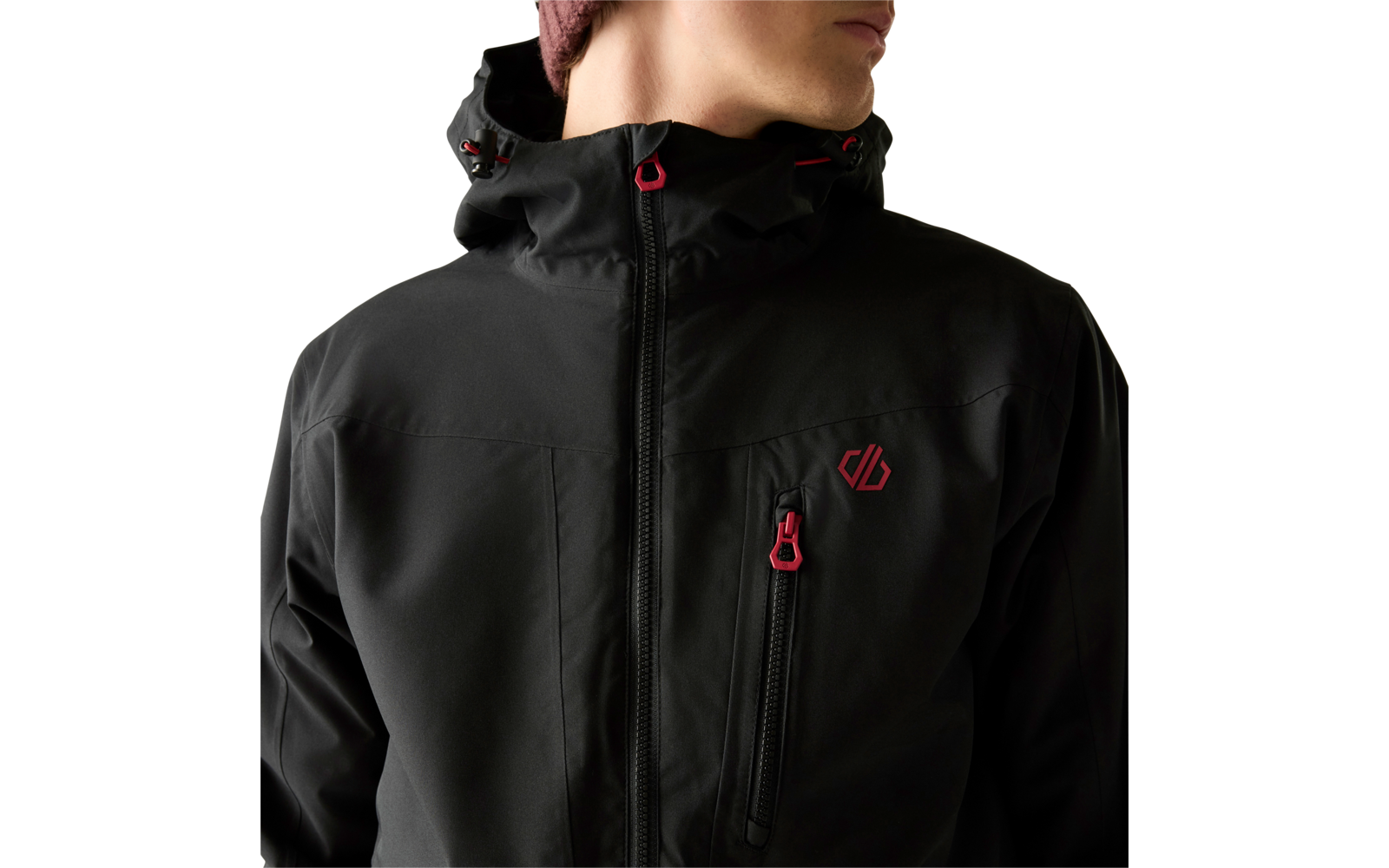 Oberkörper einer Person in schwarzer Kapuzenjacke mit roten Zippern, kleinem roten Logo auf der Brust und Mütze; Gesicht teilweise sichtbar, Blick nach rechts