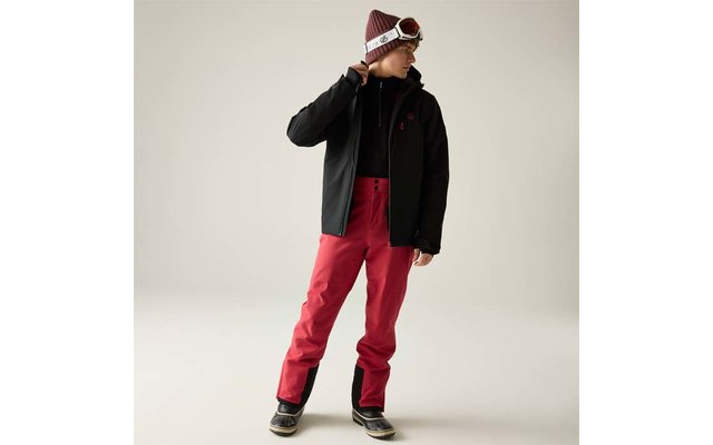 Person in schwarzer Jacke, roter Hose, Mütze und Skibrille, steht und blickt zur Seite