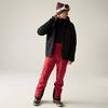 Person in schwarzer Jacke, roter Hose, Mütze und Skibrille, steht und blickt zur Seite
