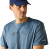 Mann mit dunkelblauer Baseballkappe, blaues T-Shirt mit kleinem Brustmotiv und Logoprint auf dem Ärmel, Blick nach links