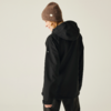 Person von hinten, trägt schwarze Kapuzenjacke und braune Mütze