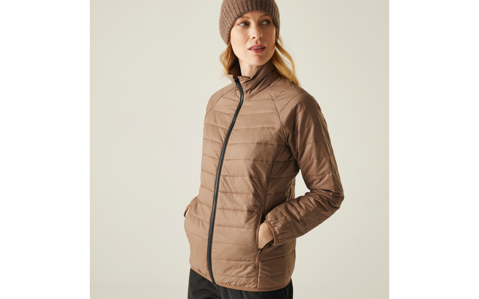 Frau trägt eine beige Steppjacke und eine graue Mütze