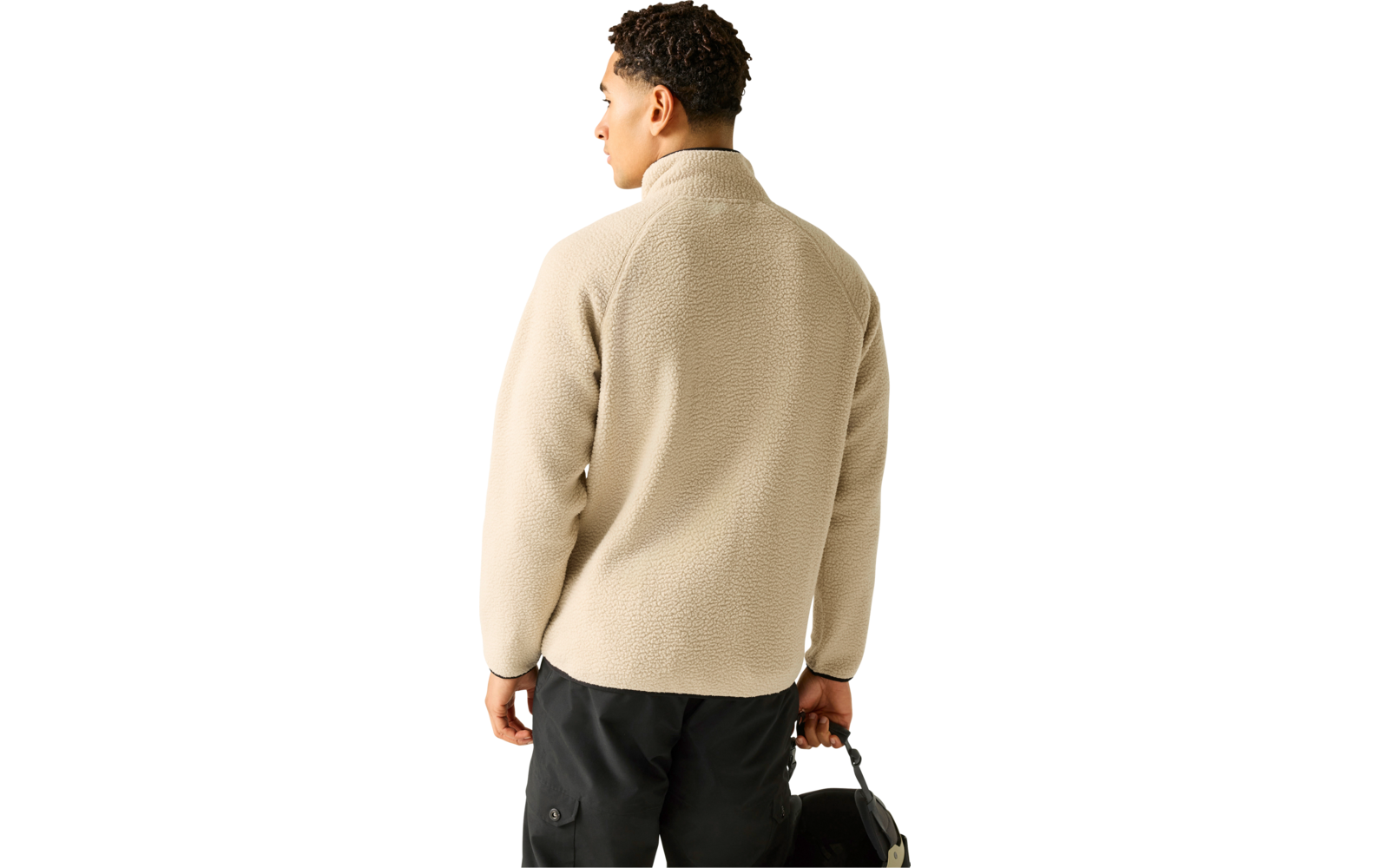 Person von hinten, kurz lockiges dunkles Haar, trägt beige Fleecejacke mit Stehkragen und schwarze Hose, hält schwarze Tasche in der rechten Hand, Kopf leicht nach links gedreht