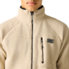 Oberkörper einer Person bis zum Kinn, trägt beigefarbene Fleecejacke bis zum Hals, Brusttasche mit Reißverschluss und Markenpatch DARE2B