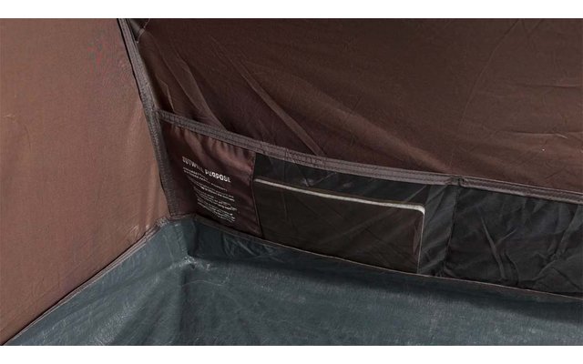 Ecke eines Innenraums aus dunkelbraunem Stoff mit grauem Boden, eingenähter Tasche mit transparentem Fenster und Etikett