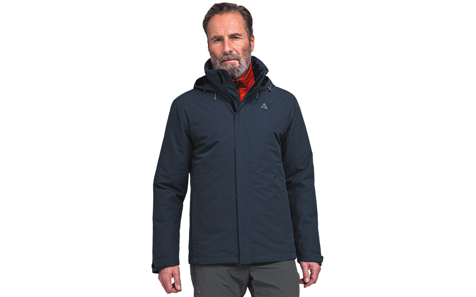 Ein Mann mit grauem Bart trägt eine dunkelblaue Kapuzenjacke und darunter eine rote Jacke, er steht vor weißem Hintergrund