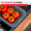 Plateau gris-bleu dans l'évier avec des gouttes d'eau, quatre tomates rouges avec tiges vertes et un poivron rouge, à côté d'un plan de travail en bois