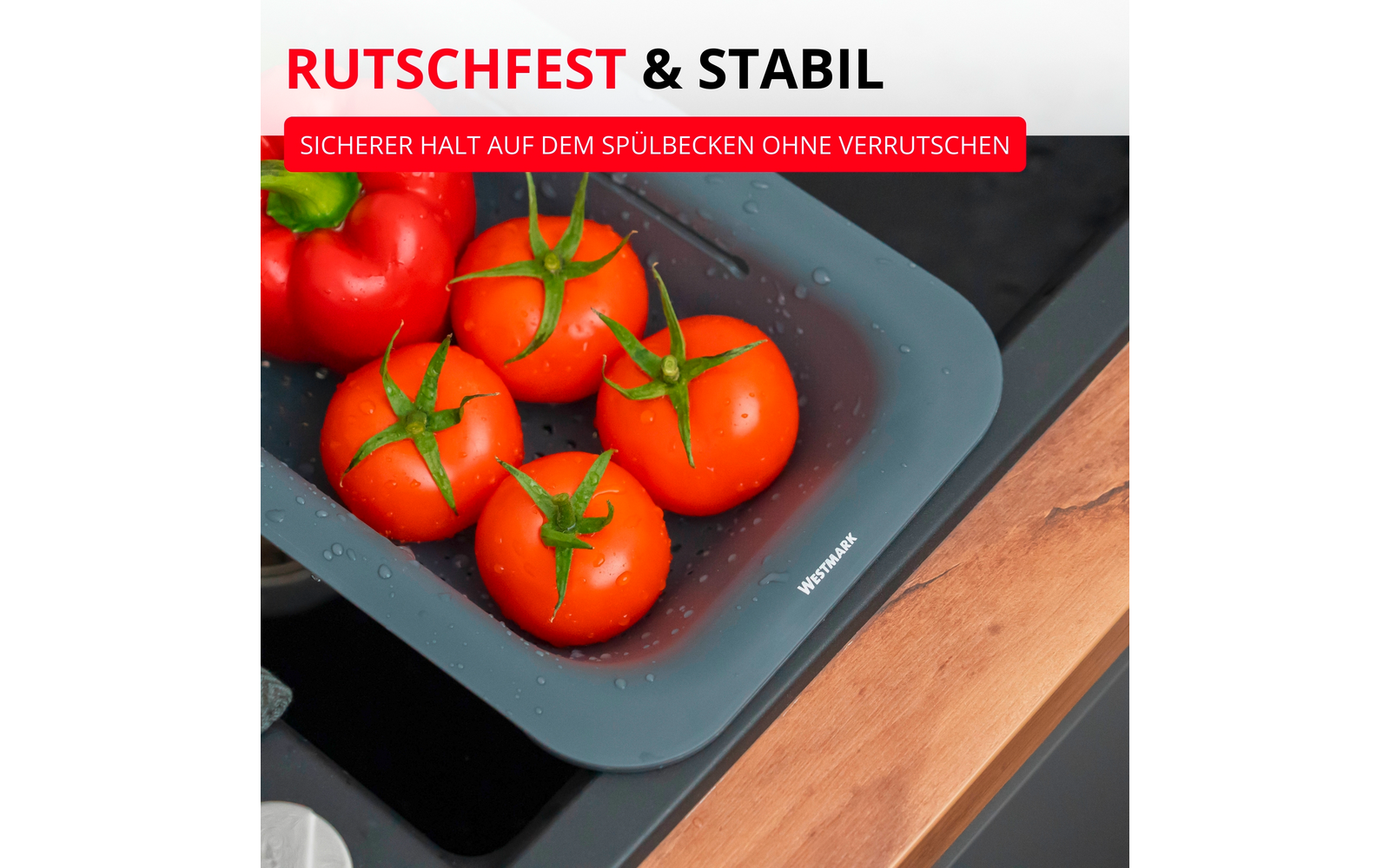 Plateau gris-bleu dans l'évier avec des gouttes d'eau, quatre tomates rouges avec tiges vertes et un poivron rouge, à côté d'un plan de travail en bois