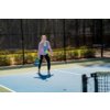 Frau spielt Tennis auf einem Außenplatz
