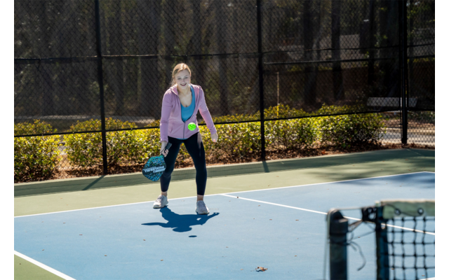 Frau spielt Tennis auf einem Außenplatz