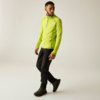 Homme en haut à manches longues vert néon avec petit zip, pantalon noir et chaussures de randonnée noires, marchant et regardant sur le côté sur fond clair