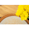 Zwei überlappende Keramikteller mit feinem Rissmuster auf hellem Holztisch, rechts angeschnittene gelbe Blumen