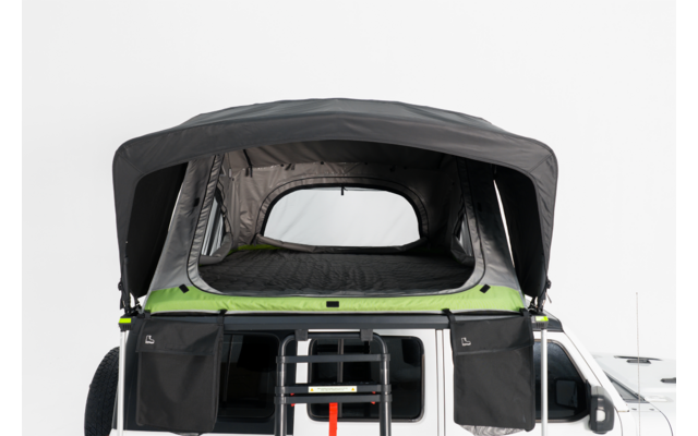 Aufgeklapptes Dachzelt auf einem weißen Camper-Van, Front geöffnet, Leiter angebracht, Matratze und seitliche Aufbewahrungstaschen sichtbar