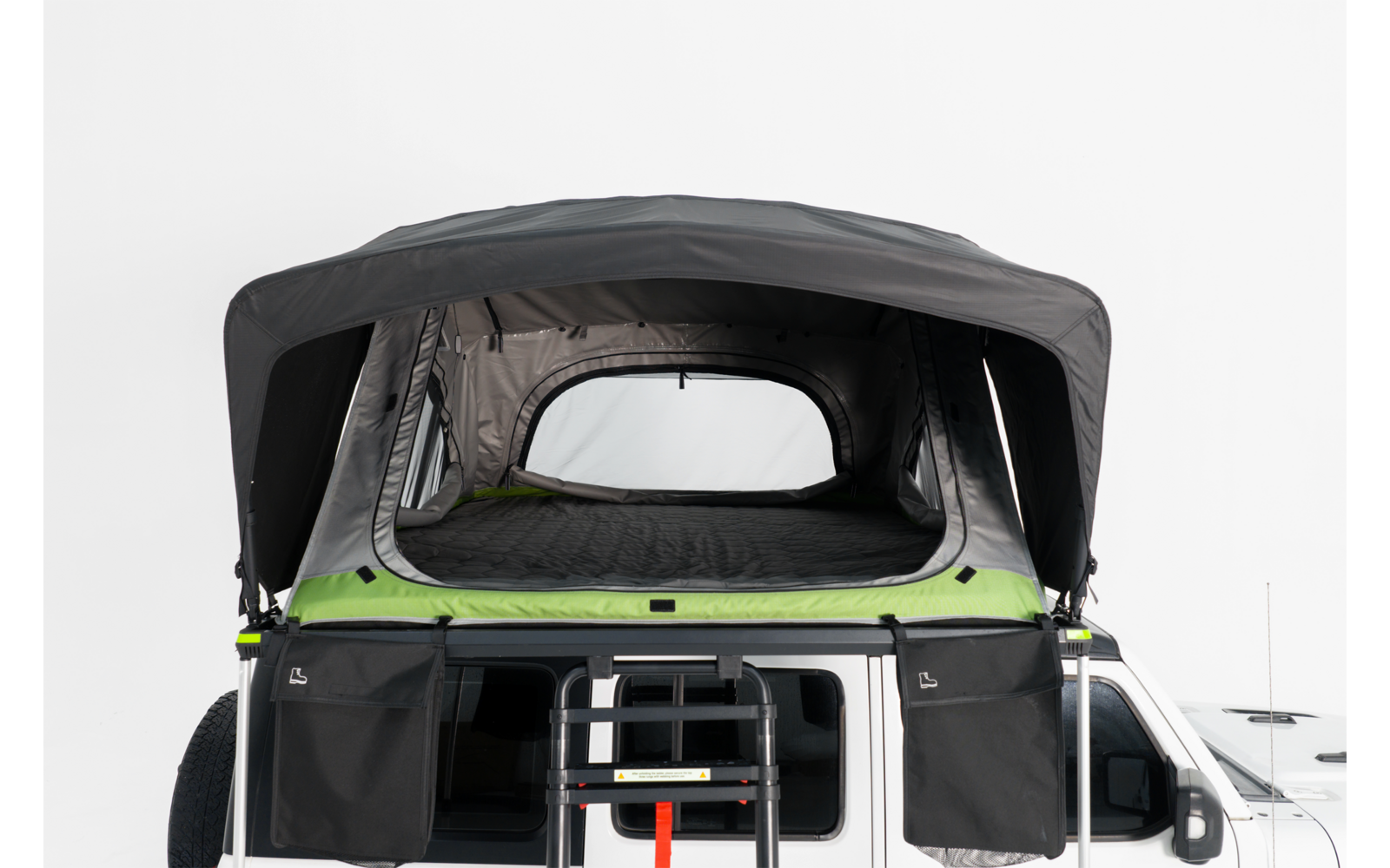 Aufgeklapptes Dachzelt auf einem weißen Camper-Van, Front geöffnet, Leiter angebracht, Matratze und seitliche Aufbewahrungstaschen sichtbar