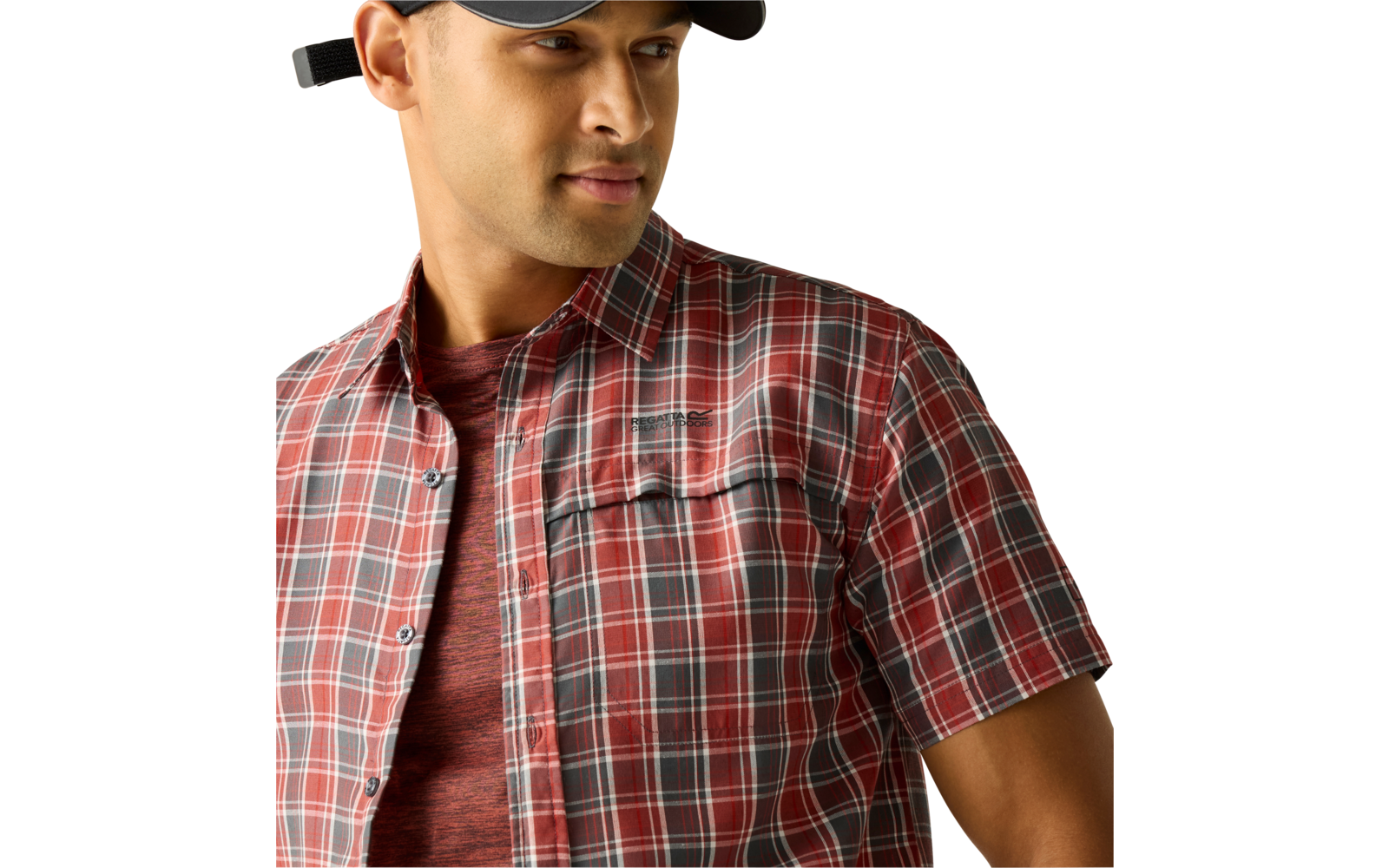 Person mit schwarzer Kappe, rotem kariertem Kurzarmhemd über rotem T‑Shirt, Blick nach rechts, heller einfarbiger Hintergrund, Bildausschnitt bis zur Brust