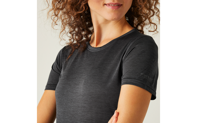 Teilansicht einer Person von Brust bis Kinn, lockiges braunes Haar, dunkelgraues kurzärmeliges T-Shirt, Arme gekreuzt, leichtes Lächeln