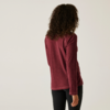 Frau mit lockigem Haar, die von hinten zu sehen ist, trägt ein rotes Langarmshirt und schwarze Hose