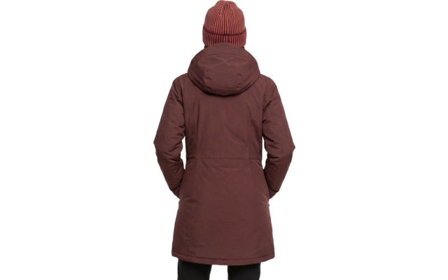 Persoon van achteren, draagt een bruin heuplang parka met capuchon en een roodbruine geribde muts; handen in de zijzakken, zwarte broek zichtbaar