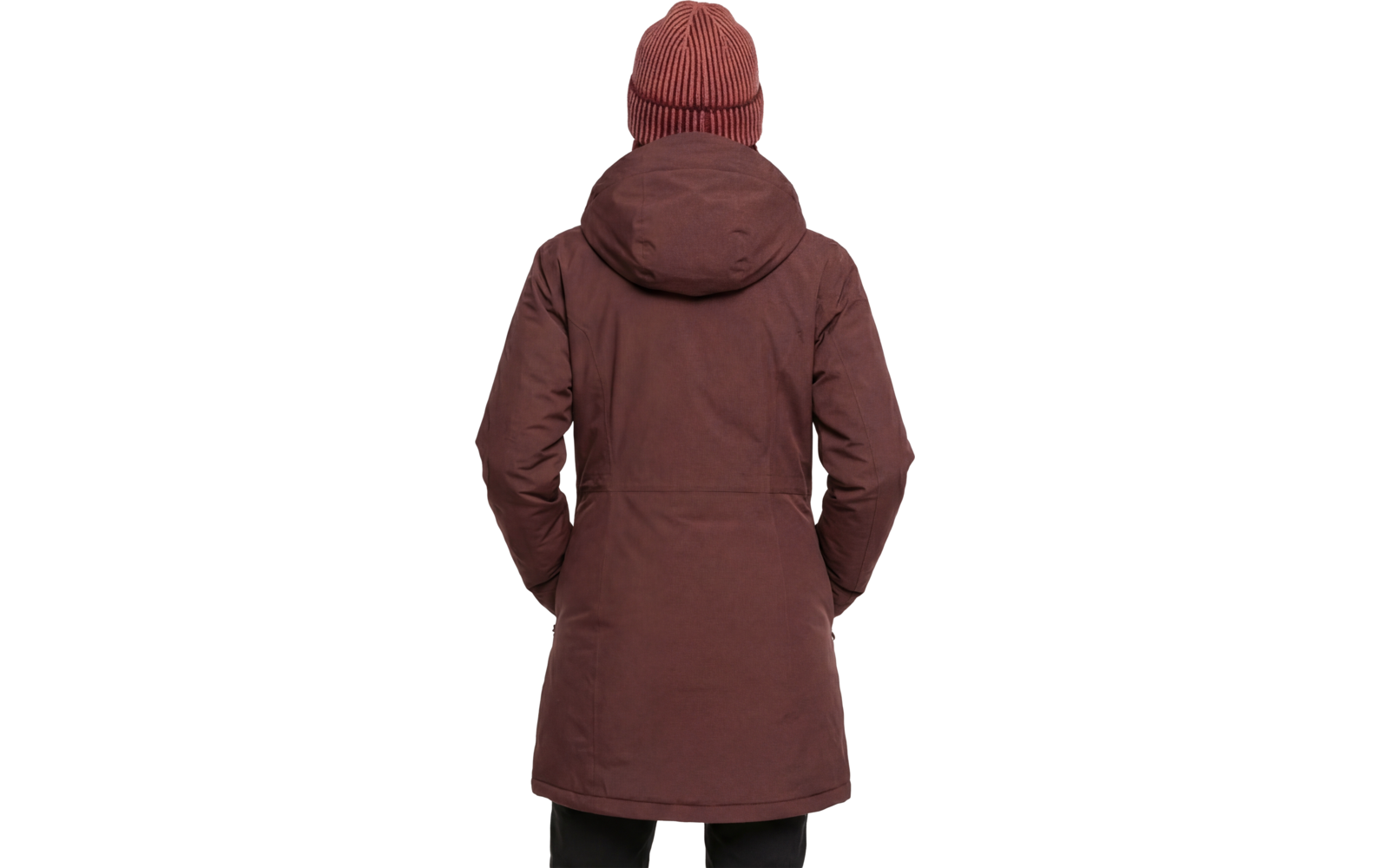 Persoon van achteren, draagt een bruin heuplang parka met capuchon en een roodbruine geribde muts; handen in de zijzakken, zwarte broek zichtbaar