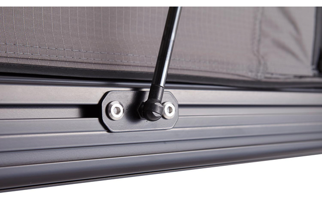 Nahaufnahme eines schwarzen Metallrahmens mit Rillen, einer schwarzen Stange mit Gelenk, befestigt mit sichtbaren Schrauben, und einem grauen Stoffnetz im Hintergrund