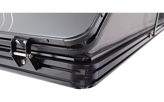 Nahaufnahme der Ecke eines schwarzen Hartschalenkoffers mit sichtbarem Metallverschluss und mehrlagigem Kantenprofil