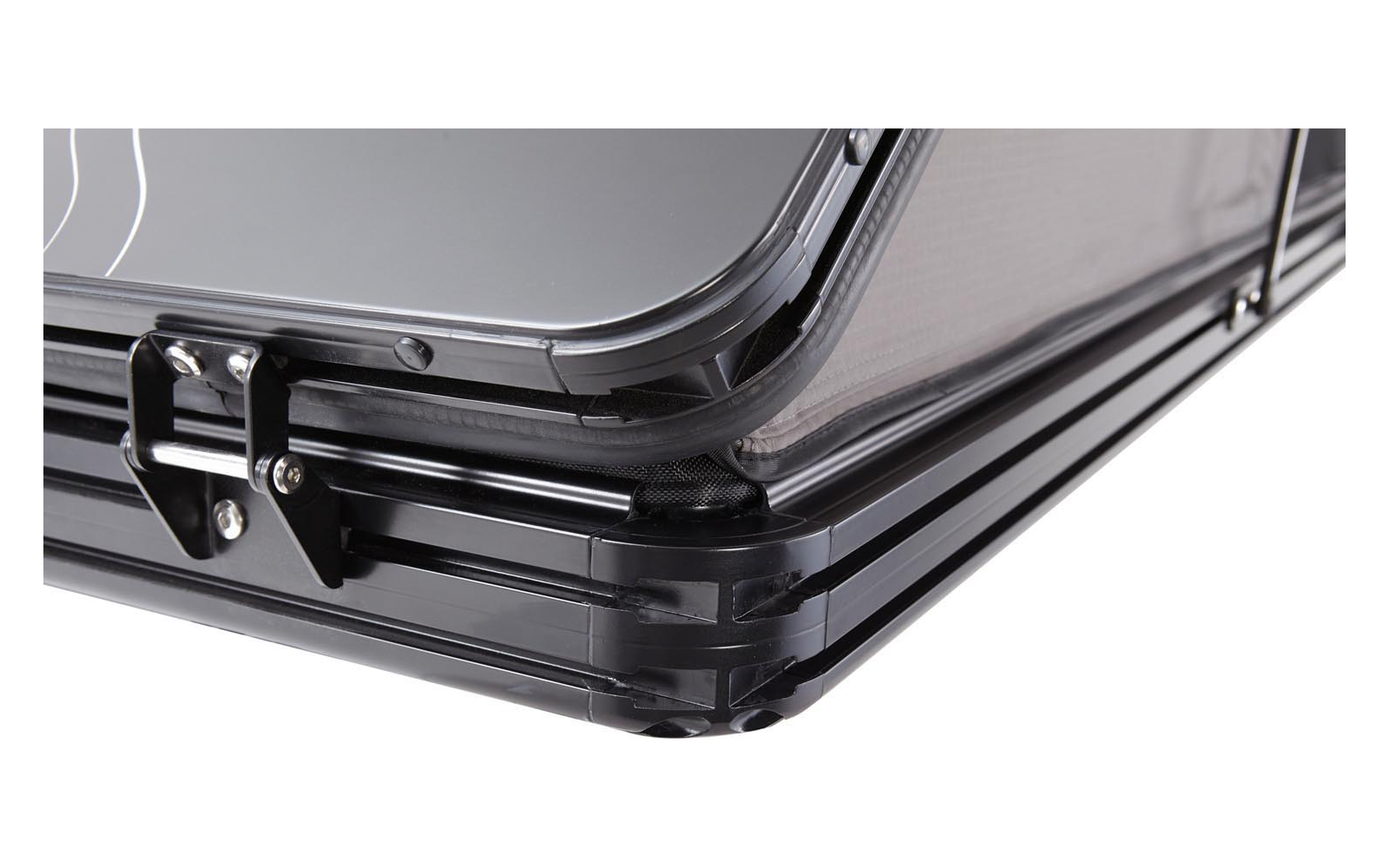 Nahaufnahme der Ecke eines schwarzen Hartschalenkoffers mit sichtbarem Metallverschluss und mehrlagigem Kantenprofil