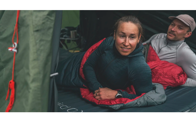 Twee personen liggen naast elkaar op de grond, één kijkt naar de camera