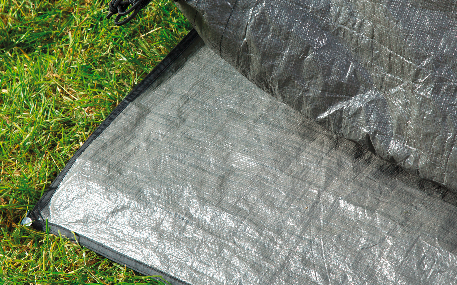 Two silver tarps stacked on green grass