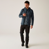 Ein Mann trägt eine blaue Jacke, ein blaues Hemd und schwarze Hose, er geht nach rechts