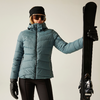Frau in blauer Winterjacke, schwarzer Mütze und Handschuhen hält einen Ski