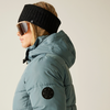 Frau seitlich, trägt eine dicke Steppjacke, Stirnband und Sonnenbrille