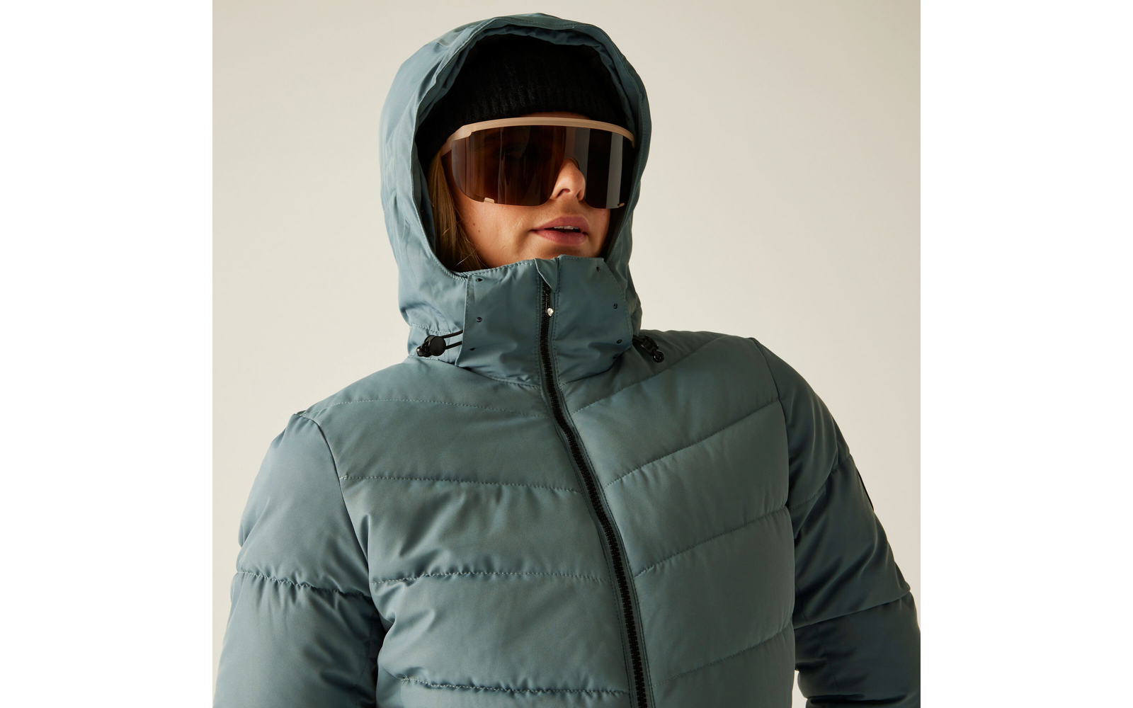 Person trägt grüne Daunenjacke mit Kapuze und Sonnenbrille