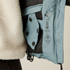Nahaufnahme des Innenfutters und der Etiketten einer hellblauen Jacke mit Teddyfellstoff an der Außenseite