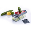 Plastic vegetable slicer with red insert; a cucumber in the top opening; thin cucumber slices in the transparent container; two whole cucumbers, a lemon and a lime beside it; removable lid next to the container