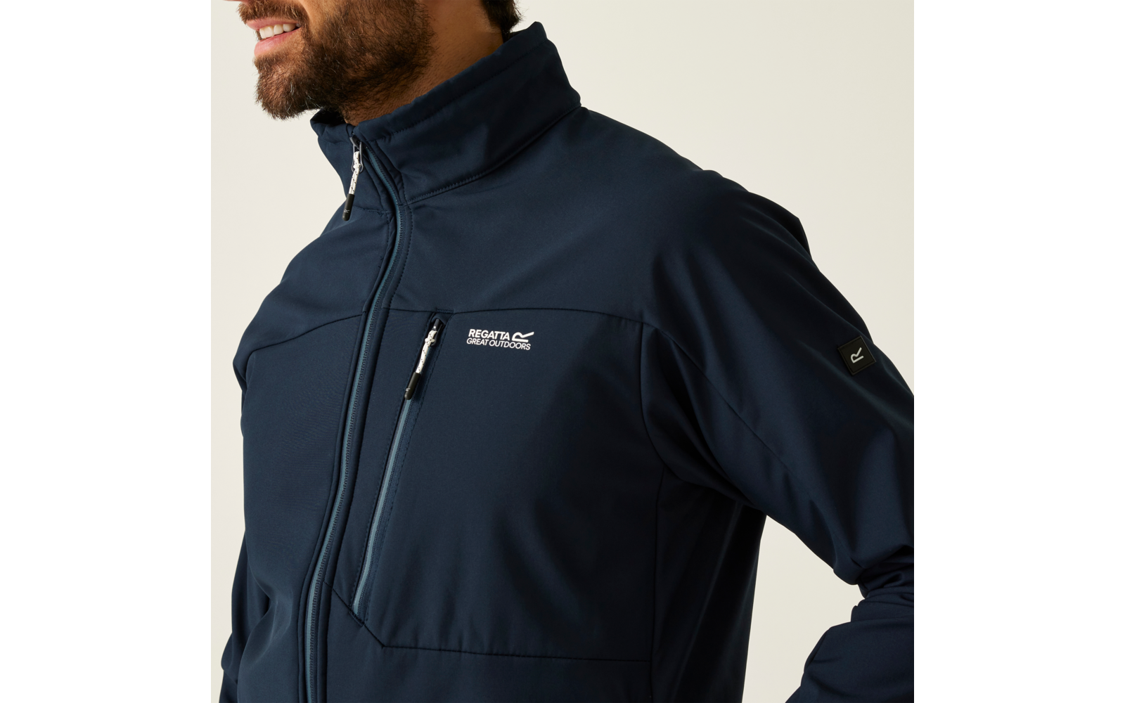 Oberkörper einer Person links im Bild; Bart und Teil des Gesichts sichtbar; dunkelblaue Jacke mit hohem Kragen, vertikalem Reißverschluss, Brusttasche und weißem 'Regatta Great Outdoors'-Logo