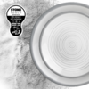 Draufsicht eines runden Tellers mit konzentrischen Ringen rechts, körnige Textur links und schwarzes Etikett oben links mit Text 'STONE TOUCH dinnerware 60% mineral 40% melamine'