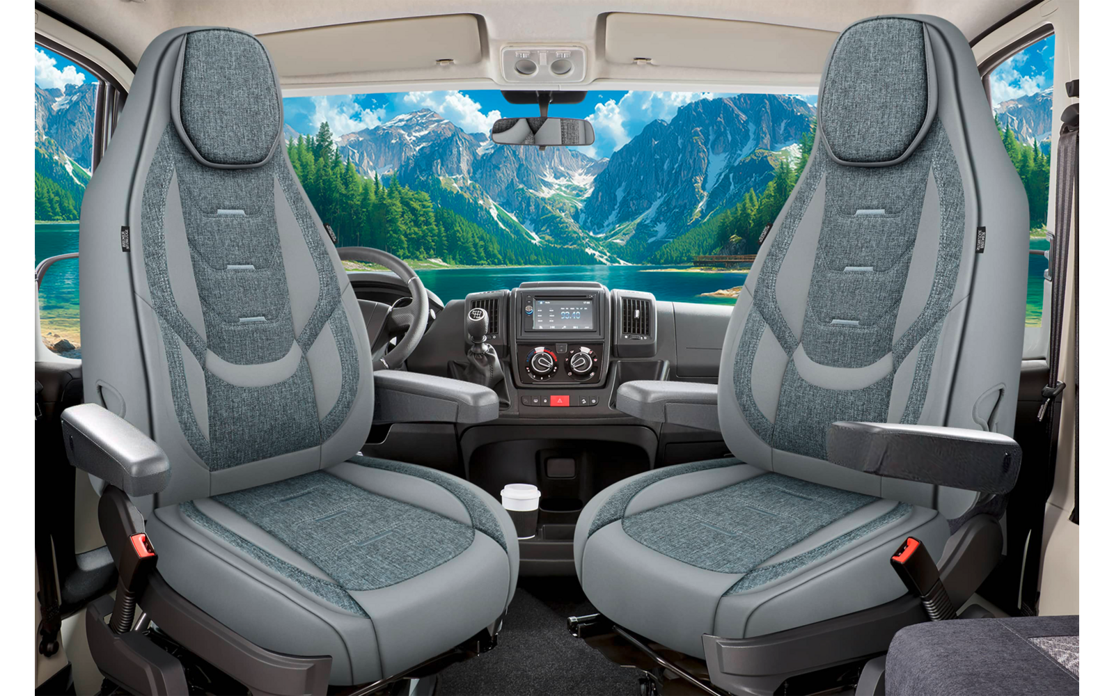 Innenraum eines Fahrzeugs mit zwei grauen Vordersitzen mit Armlehnen und Sicherheitsgurten, Armaturenbrett und Lenkrad, Blick durch die Windschutzscheibe auf einen türkisfarbenen See und bewaldete, schneebedeckte Berge