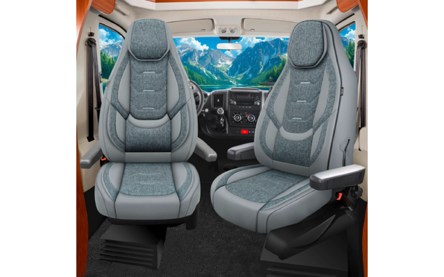 Zwei graue, gepolsterte Vordersitze mit Armlehnen vor Armaturenbrett und Lenkrad; durch die Windschutzscheibe sichtbare Berglandschaft