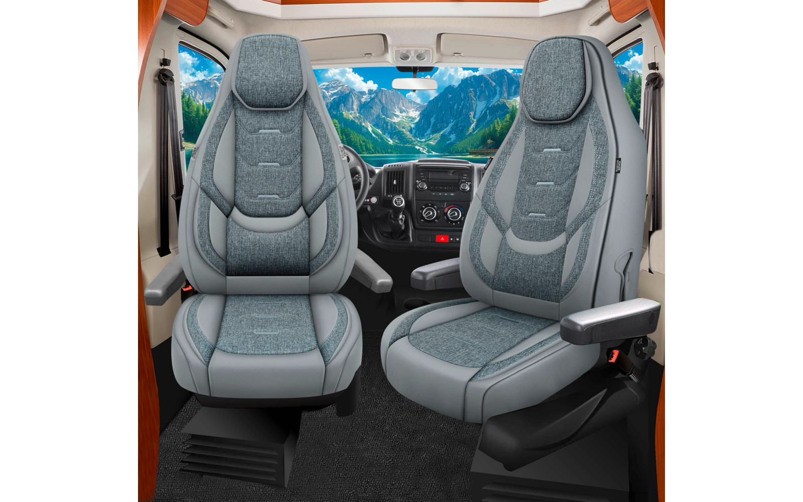 Zwei graue, gepolsterte Vordersitze mit Armlehnen vor Armaturenbrett und Lenkrad; durch die Windschutzscheibe sichtbare Berglandschaft