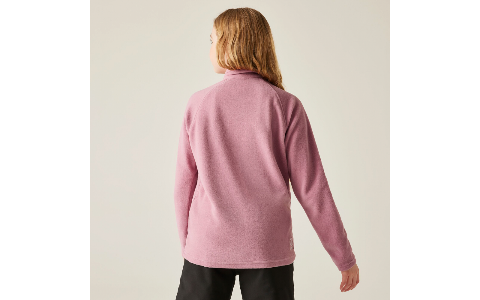Frau von hinten mit rosa Pullover und schwarzer Hose vor hellem Hintergrund