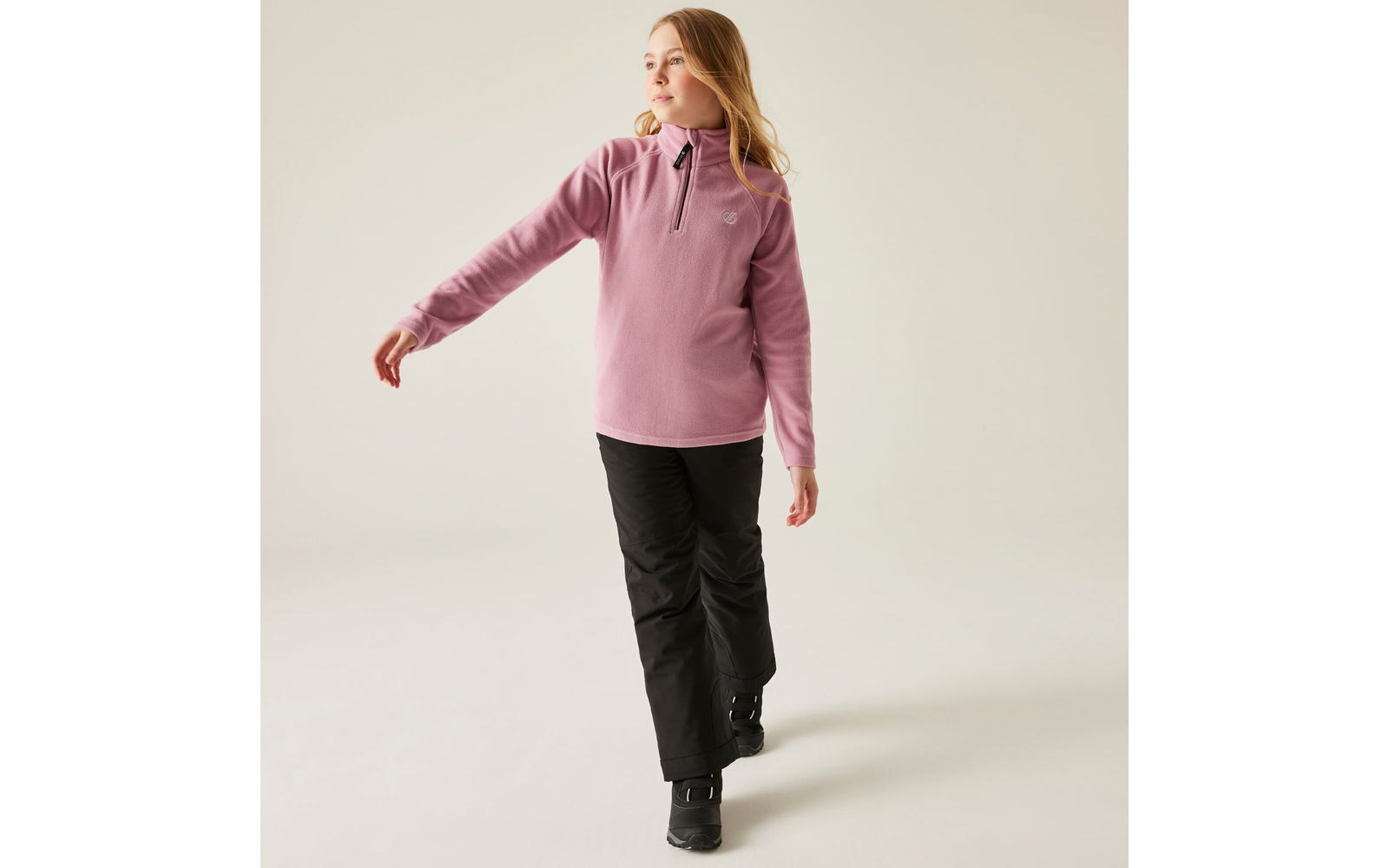 Frau in rosa Pullover und schwarzer Hose steht, eine Hand ausgestreckt