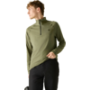 Personne portant un haut manches longues olive avec une courte fermeture éclair et petit logo, pantalon noir, regardant vers la gauche et tenant l'ourlet de la main droite, fond clair