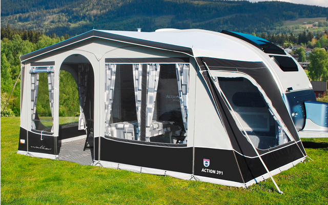 Black and white motorhome awning on a green lawn with mountains in the background