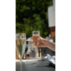 Hand houdt een glas met bruisende drank, andere glazen en een groene achtergrond