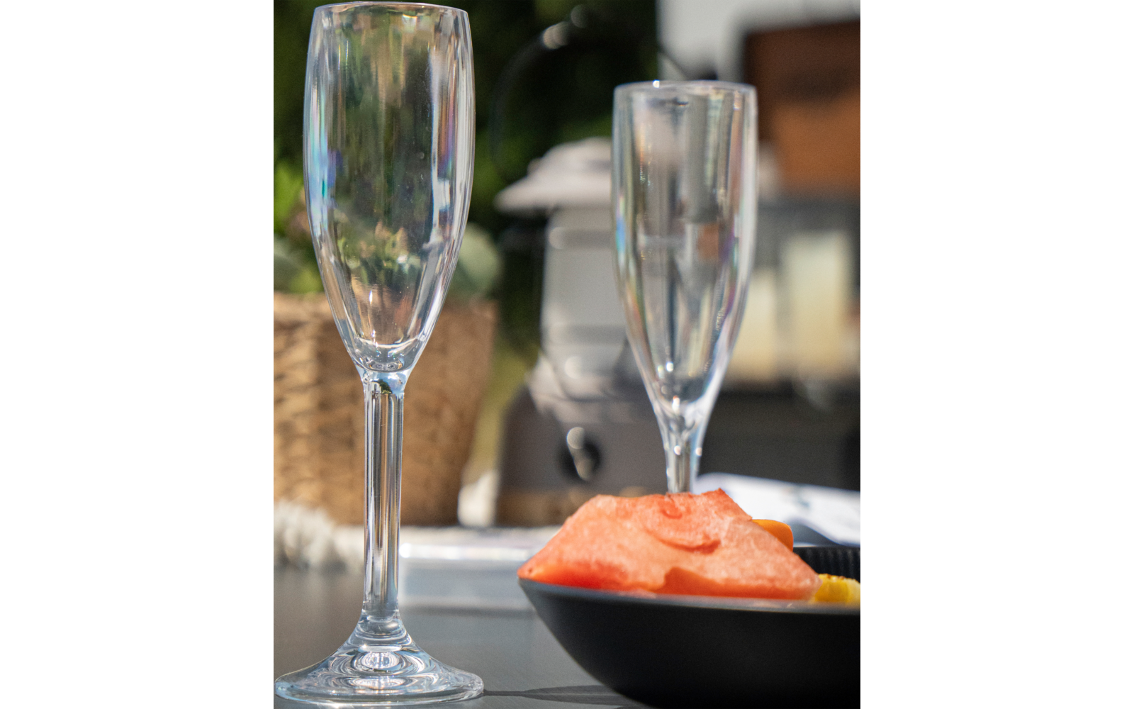 Twee lege champagneglazen naast een zwarte schaal met zalm