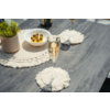 Table en bois grise avec deux dessous de verre macramé, au premier plan une flûte contenant un liquide doré clair, en arrière-plan une autre flûte, un bol d'olives vertes sur des pics et une petite plante en pot