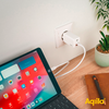 Tablet mit offenem Bildschirm, das über ein weißes Ladekabel mit einer Steckdose verbunden ist