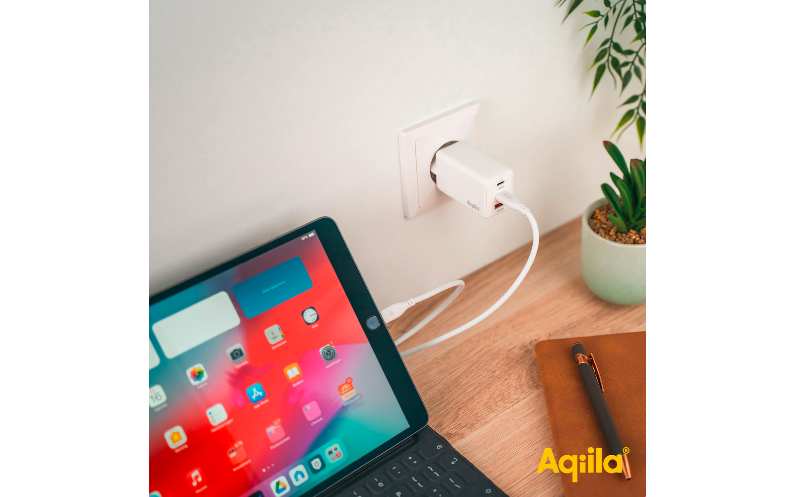 Tablet mit offenem Bildschirm, das über ein weißes Ladekabel mit einer Steckdose verbunden ist