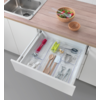 Offene Küchenschublade mit Besteck und Küchenutensilien, darüber Küchenarbeitsfläche mit Spüle und Schalen